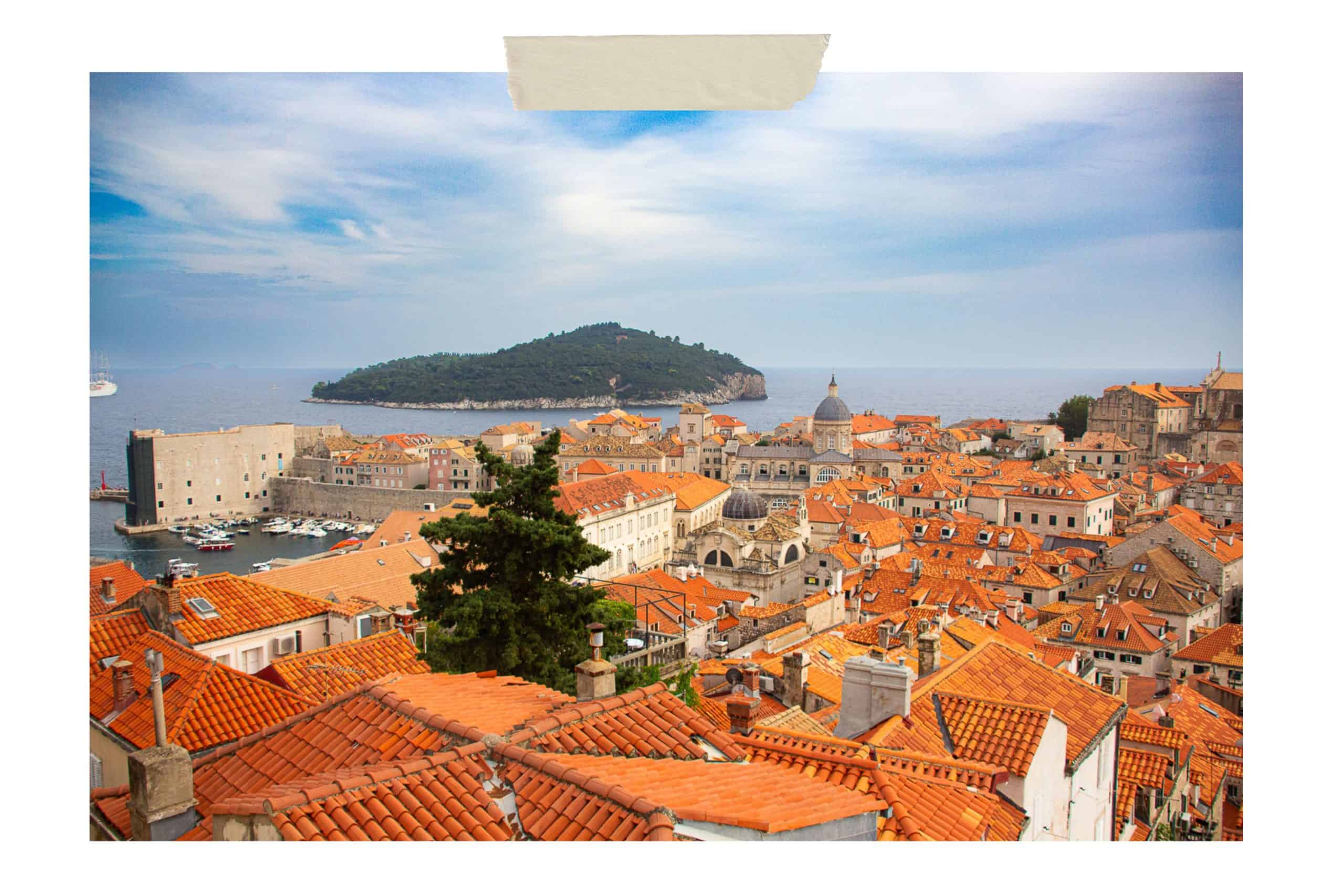 One of the top things to do in Dubrovnik is to visit the island of Lokrum. This picture shows Lokrum in the distance over the red-roofed tops of Old Town buildings.