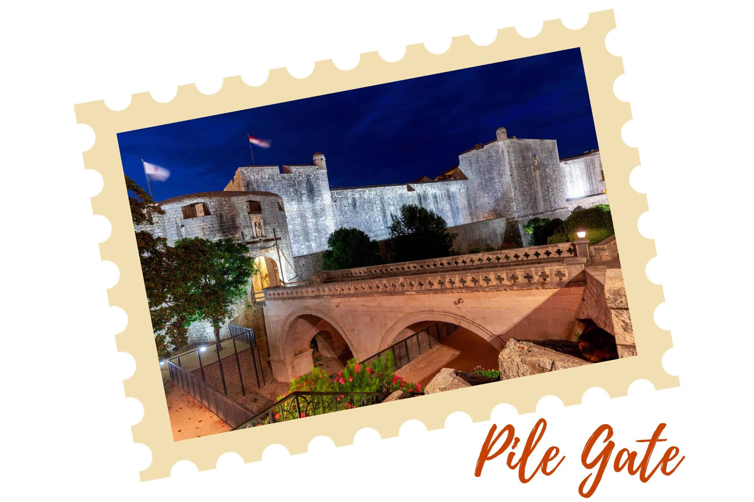 A beautiful nighttime view of Pile Gate in Dubrovnik with the bridge that leads to the entrance in the foreground and the entrance to the left with a portion of the wall in the background. The Pile neighborhood is a great location to stay for first-time visitors if you're wondering where to stay in Dubrovnik.