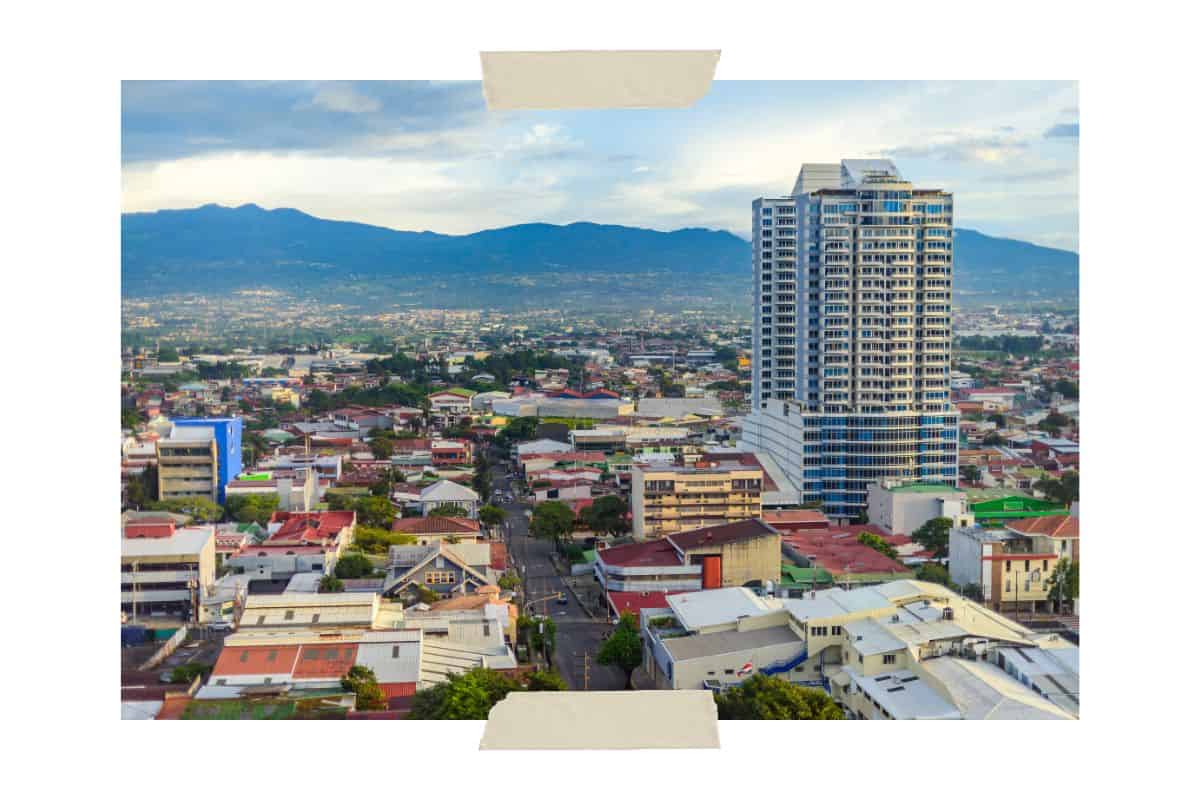 A picture showing downtown San Jose, Costa Rica. There are buildings in the foreground and mountains in the background.