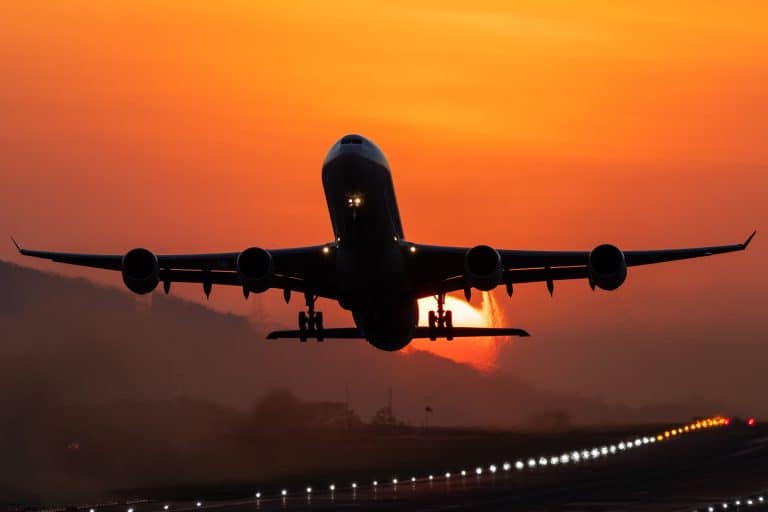 A picture of an airplane departing from Alajuela airport at sunset. The background shows the sun setting behind the airplane as it lifts off from the lit runway. Alajuela is one of several Costa Rica airports.