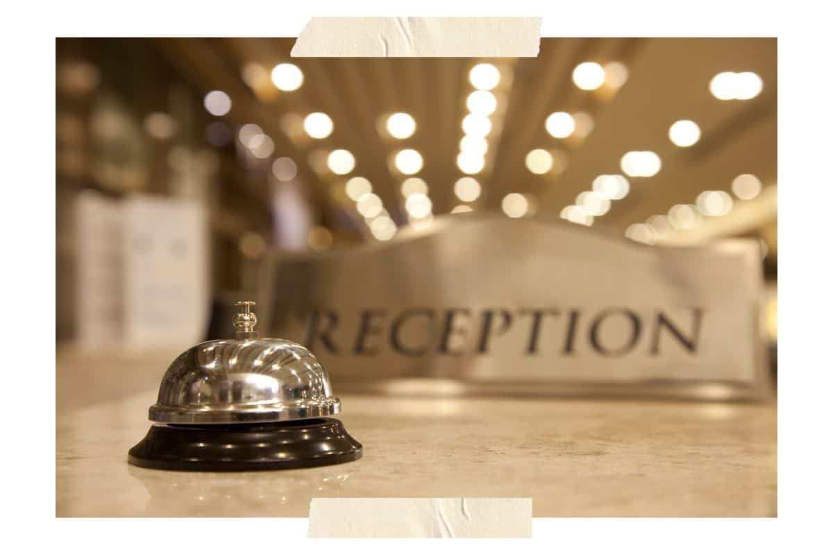 A hotel reception desk showing a bell and a sign that says reception with a faded background.