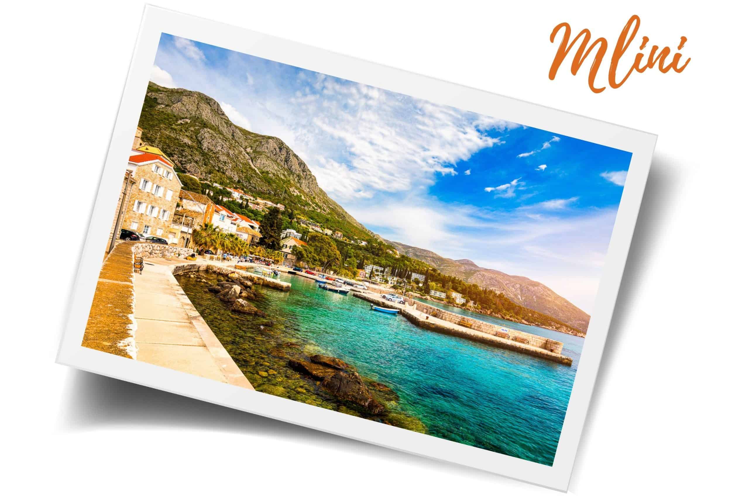 Scenic view of the coastal village of Mlini with clear turquoise waters, stone buildings, and mountains in the background – a perfect destination for day trips from Dubrovnik.