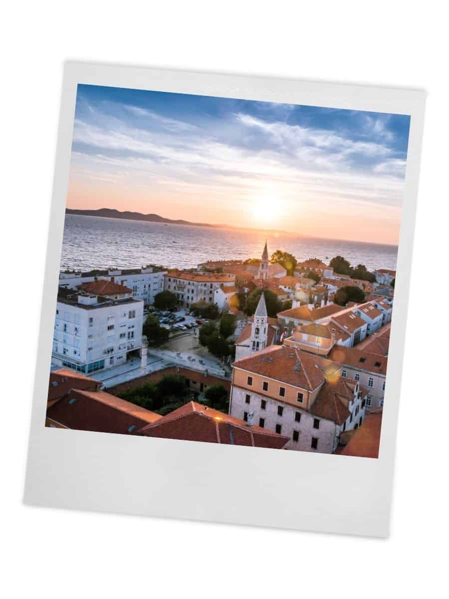 Aerial sunset view of a Croatian coastal town during the best time to visit Croatia, featuring terracotta-roofed buildings, historic church towers, and golden light reflecting off the Adriatic Sea creating perfect conditions for sightseeing