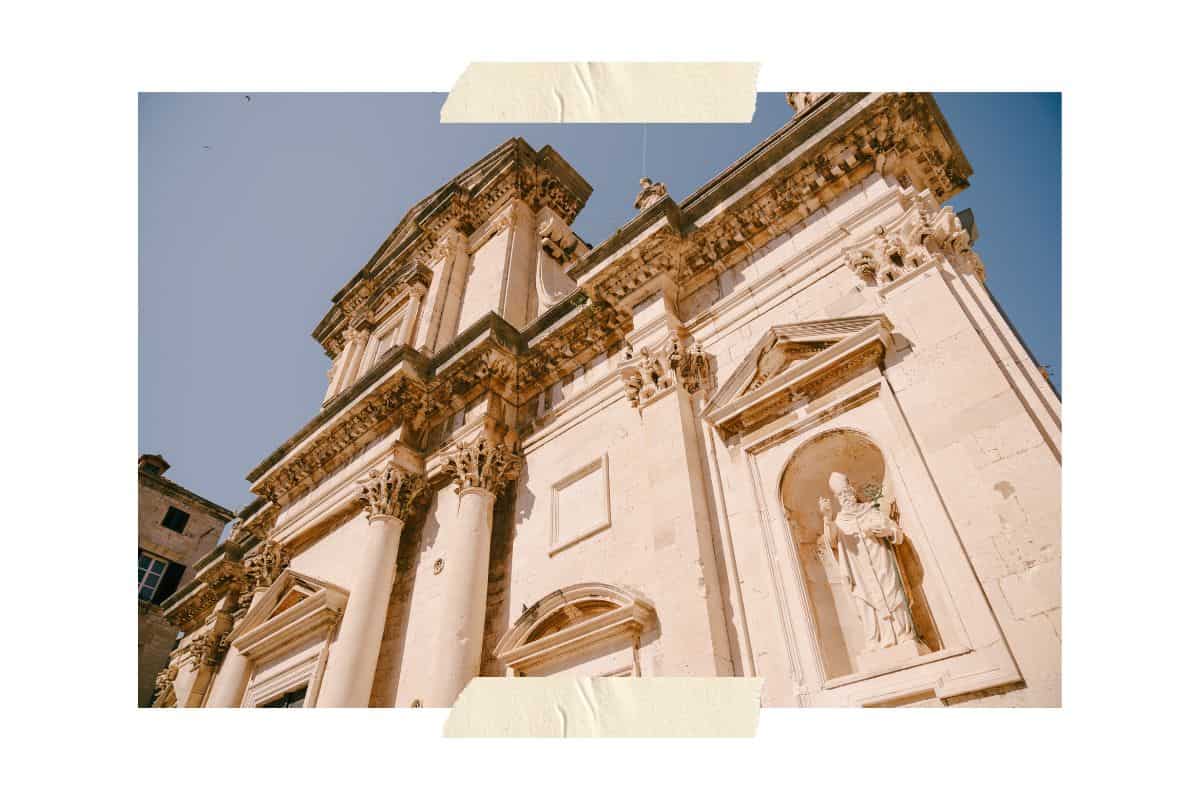 Historic baroque church facade with ornate stone columns and religious statue in Dubrovnik's Old Town - free architecture to explore in Dubrovnik