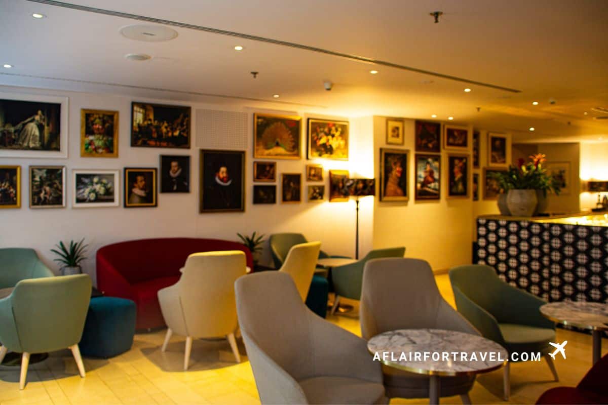 Stylish hotel lounge with colorful armchairs, gallery wall of portraits, and modern decor at Mandarin Oriental Prague
