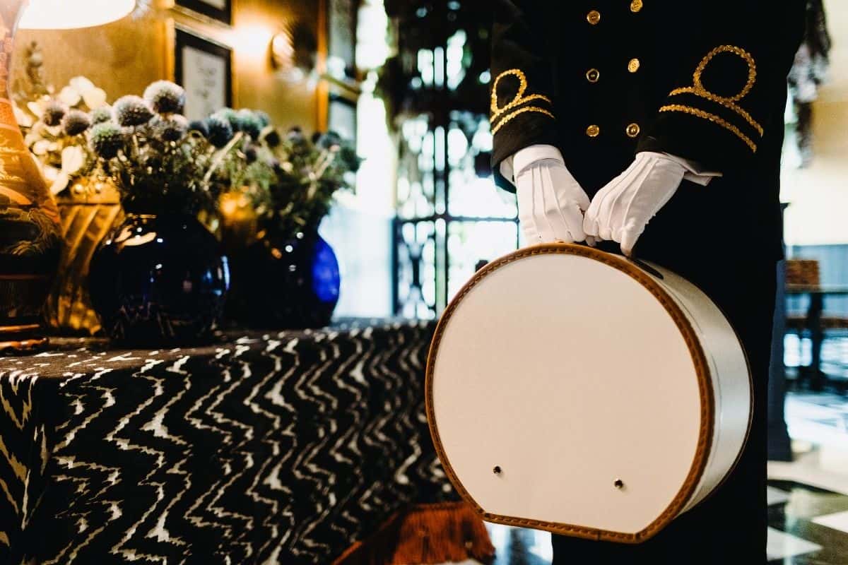 Hotel bellman in uniform with white gloves holding drum at elegant hotel lobby reception desk