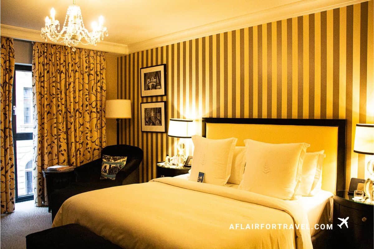 Elegant Four Seasons Prague room with striped wallpaper, chandelier, and king bed.