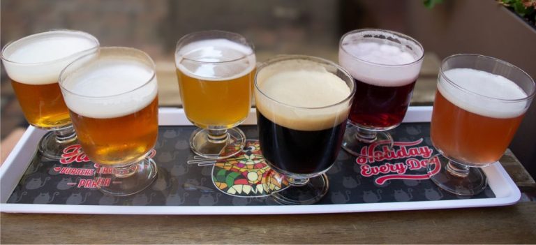 Beer tasting flight at one of the best beer spots in Prague, showing six different Czech craft beers in small glasses on a tray.