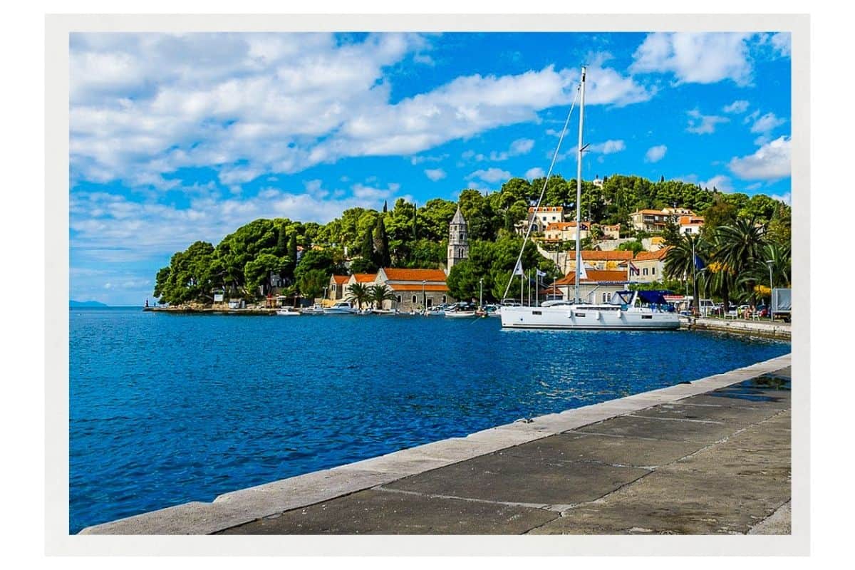 Sailboat moored in the blue Adriatic waters of Cavtat, a small coastal town in Croatia with historic buildings and lush greenery