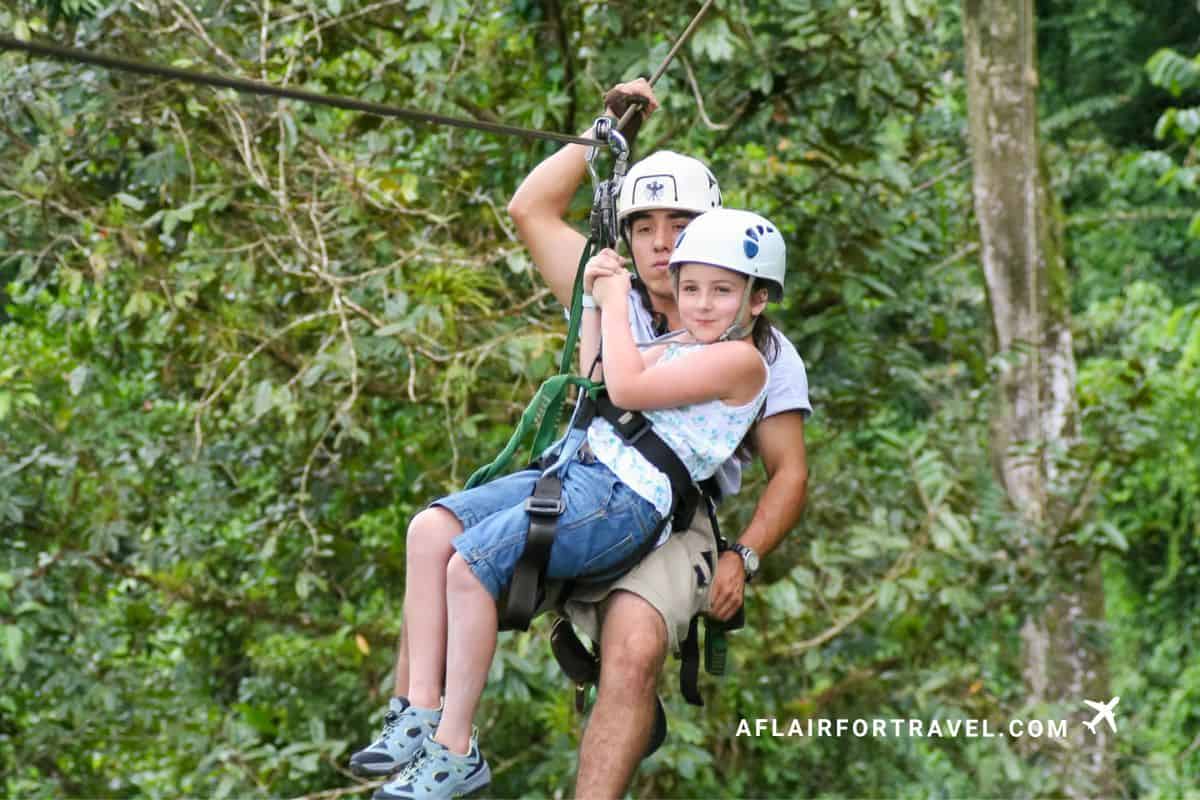 Child and guide ziplining through lush rainforest canopy in Arenal, Costa Rica