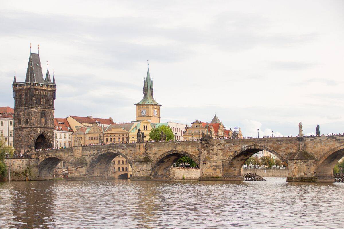 View of Charles Bridge spanning the Vltava River with historic towers and Old Town buildings in Prague