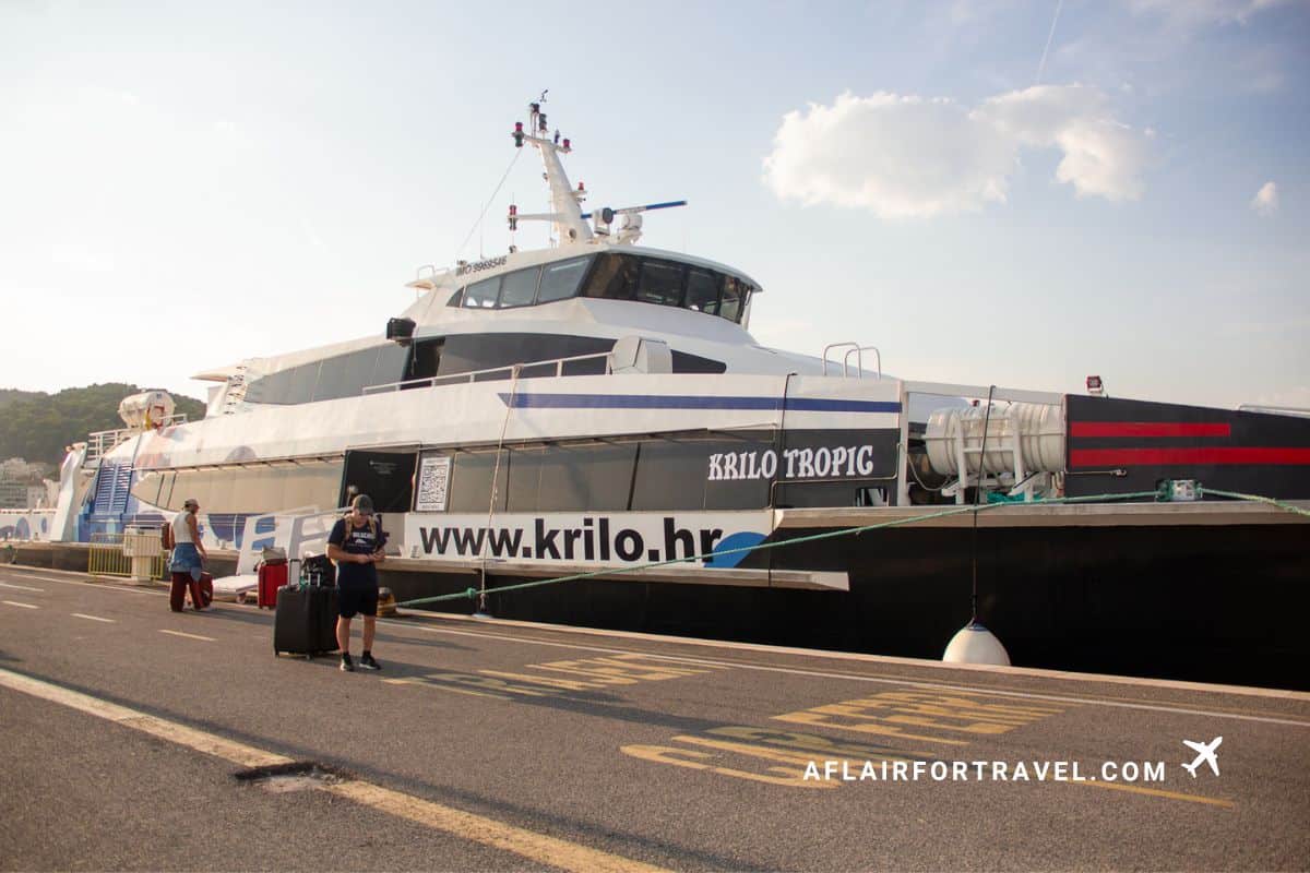 Krilo Tropic catamaran ferry docked at Split port, Croatia, with passengers boarding and forest-covered hills visible in the background, one of thevtransportation options that make Croatia worth visiting