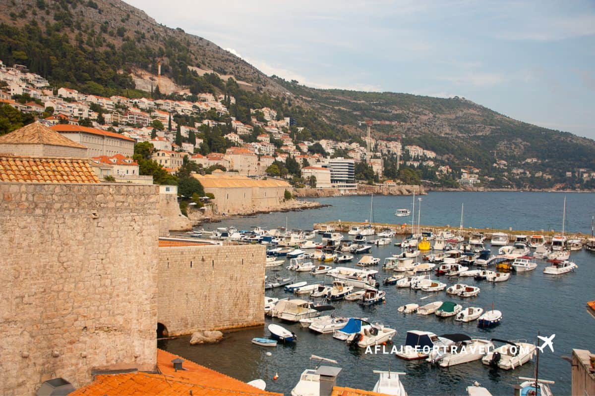 Dubrovnik’s Old Town harbor with boats, stone walls, and hillside homes along the Adriatic coast in Croatia