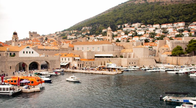 Boats in Dubrovnik’s Old Town harbor with historic city walls and hillside houses