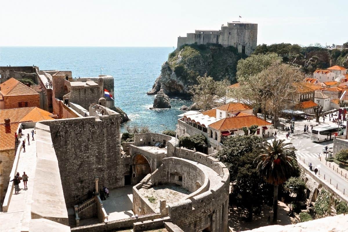 Panoramic view of Dubrovnik's ancient city walls, orange-roofed Old Town, and Fort Lovrijenac perched on a cliff above the Adriatic Sea