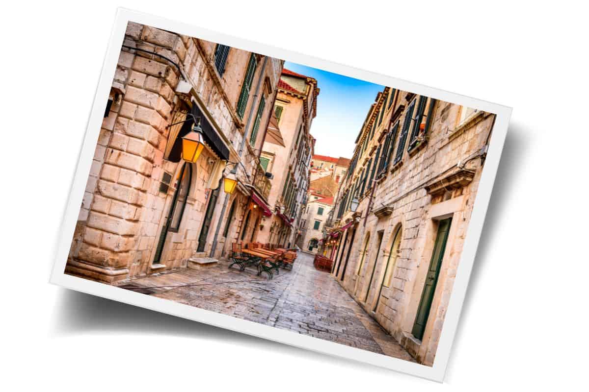 Narrow cobblestone street lined with golden lanterns and stone buildings in Dubrovnik's Old Town