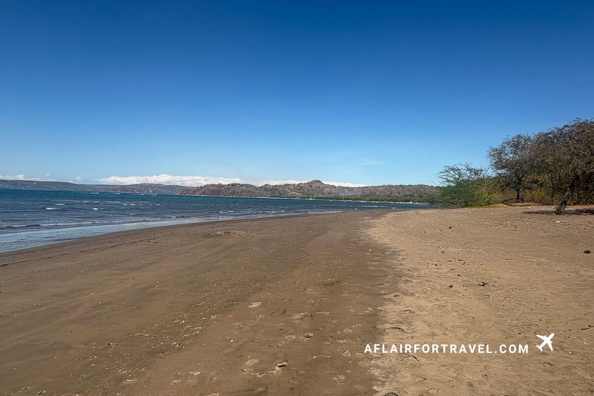 Long stretch of quiet beach in Costa Rica with soft waves and no crowds and mountains in the background