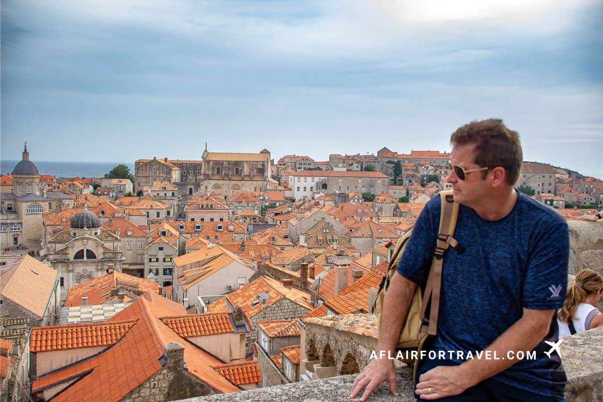 Man sitting and looking at views from Dubrovnik City Walls overlooking Old Town’s orange rooftops and Adriatic Sea