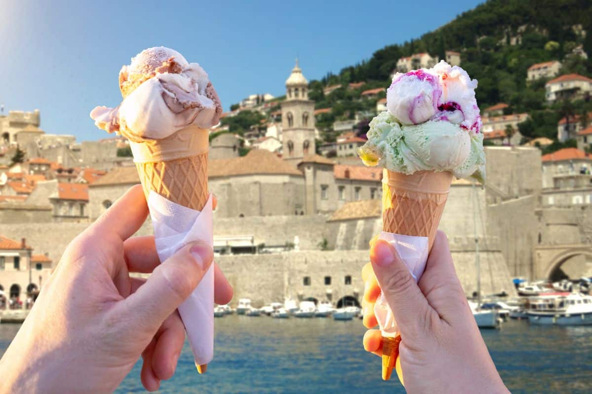 Couple holding gelato cones in front of Dubrovnik's Old Town harbor and city walls