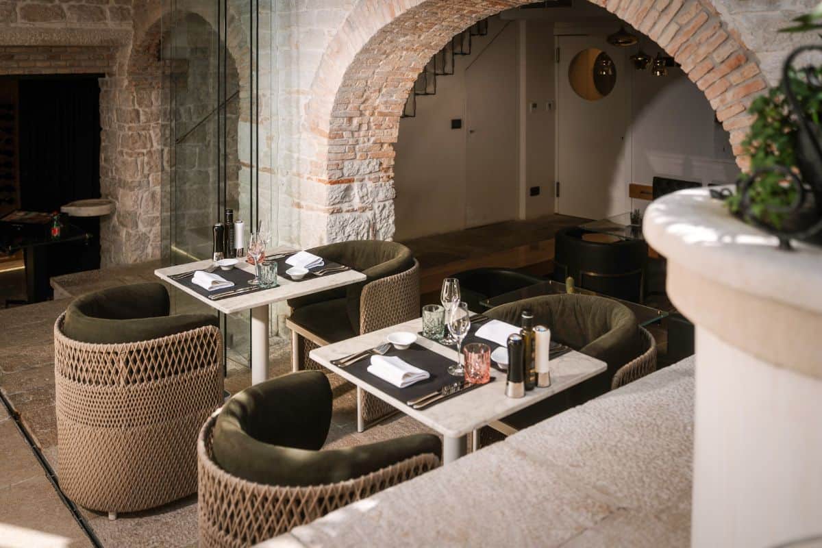 Elegant courtyard dining area inside Hotel Spirito Santo Palazzo Storico in Rovinj, a boutique hotel in Croatia, featuring exposed stone walls, arched brick architecture, and intimate seating.