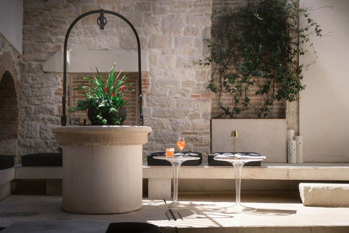 Historic courtyard at Hotel Spirito Santo Palazzo Storico in Rovinj, one of the best boutique hotels in Croatia, with a restored stone well, modern cocktail tables, and lush greenery.
