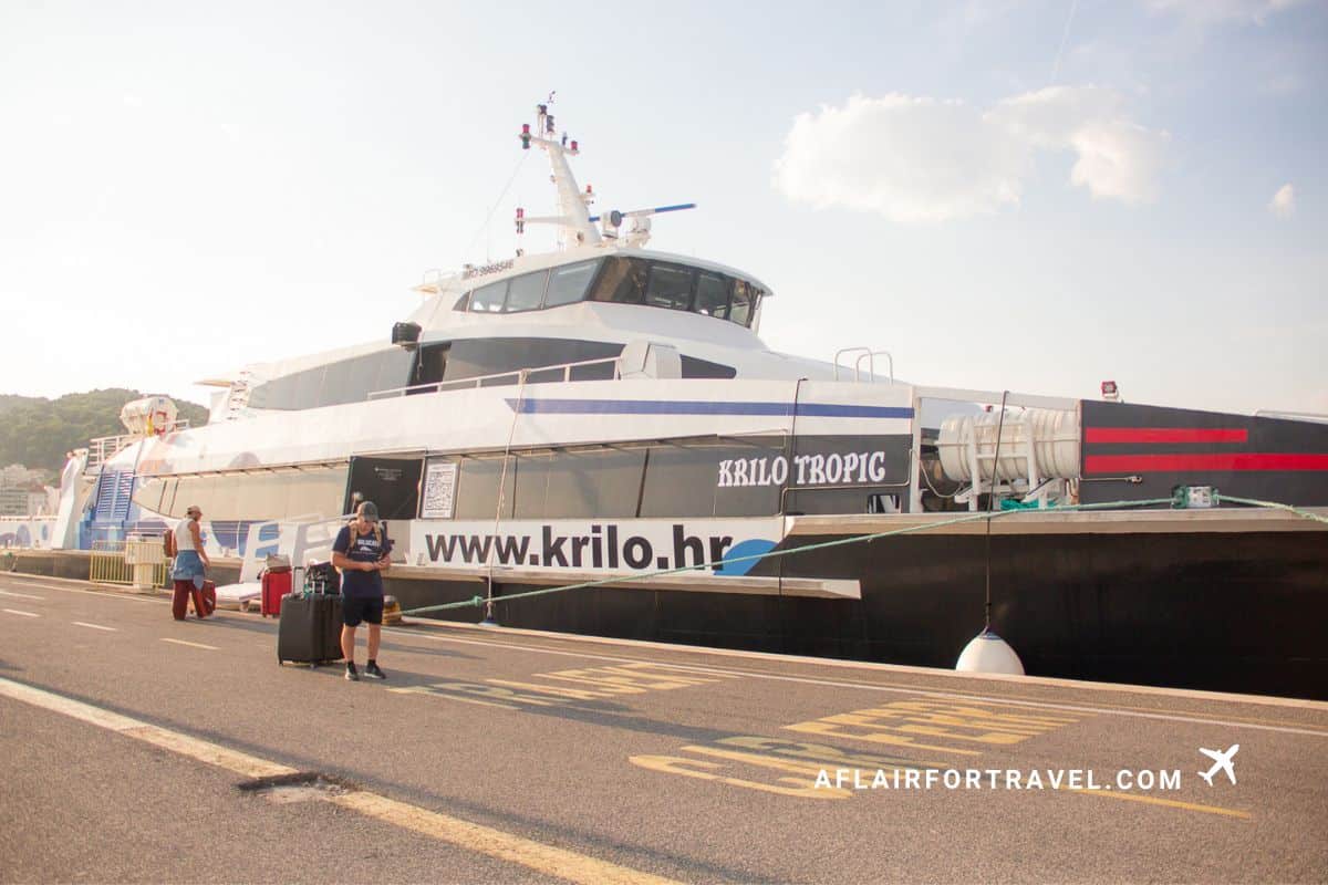A traveler with luggage boarding a Krilo high speed ferry in Croatia, a top Croatia travel tip is to check ferry schedules in advance during the off-season