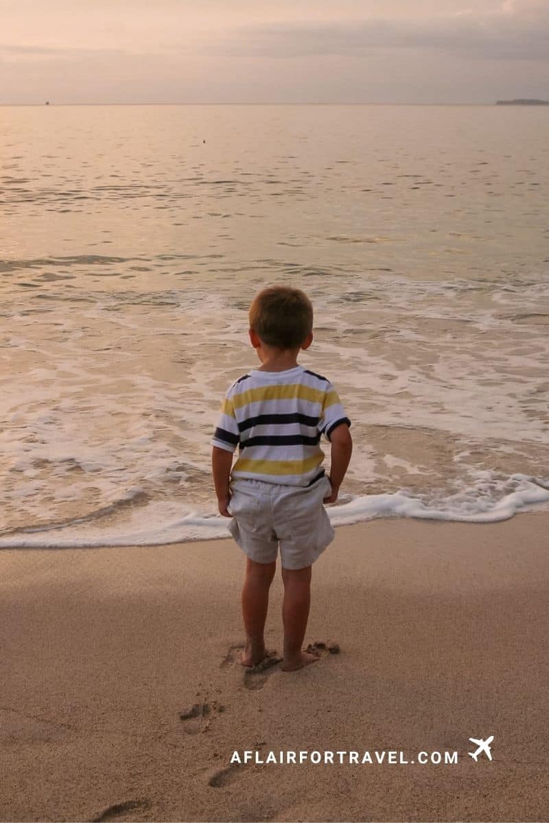 A young boy watches the waves roll in during a Costa Rica beach sunset