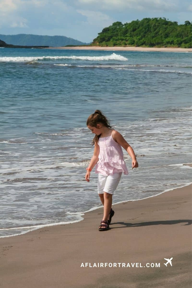 A girl walks along the shoreline in Costa Rica as waves roll in