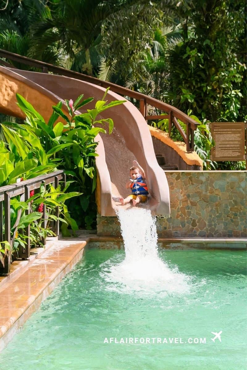 A young child splashes down a water slide at a Costa Rica hot springs pool