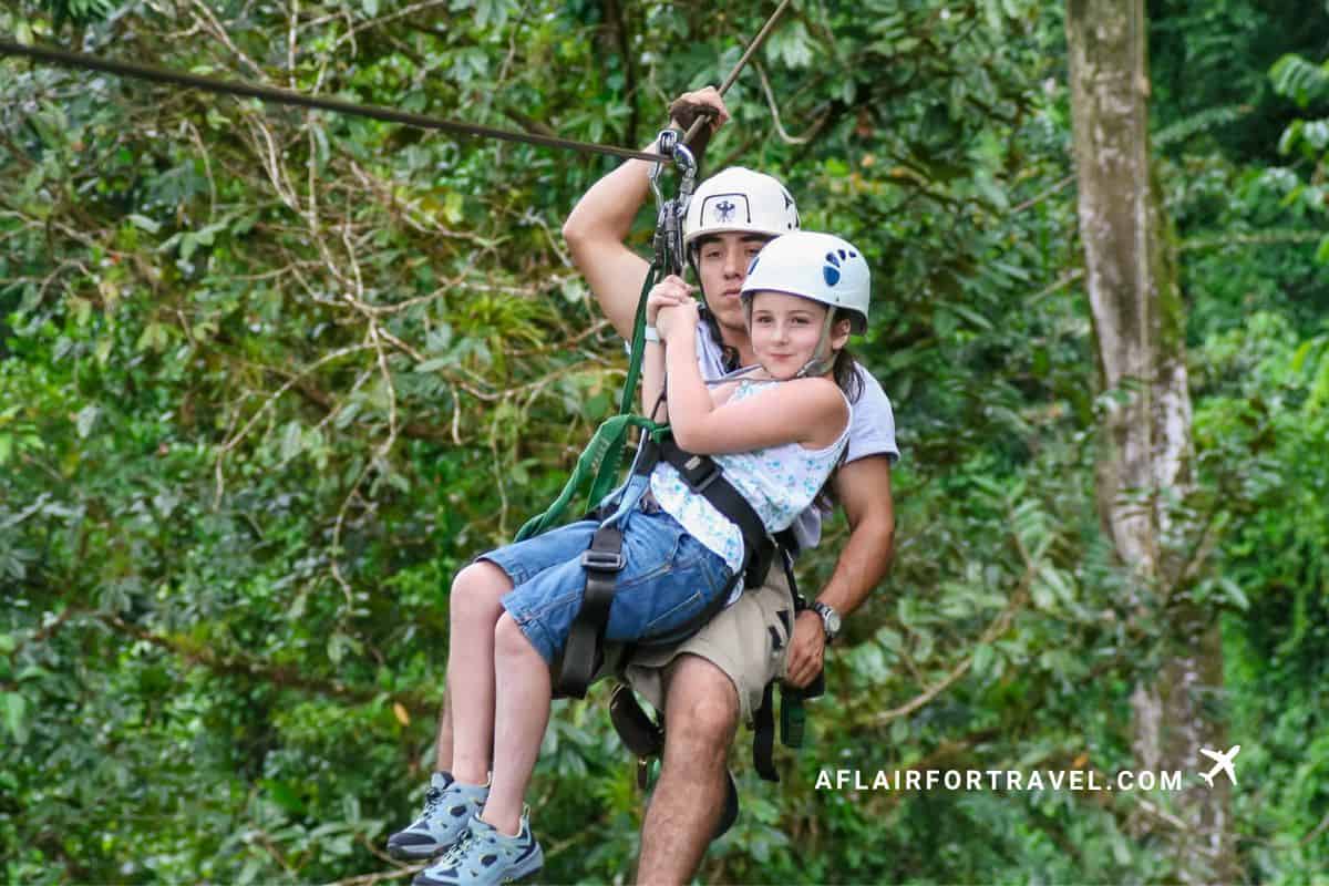 A girl ziplines tandem with her guide through the Arenal rainforest canopy