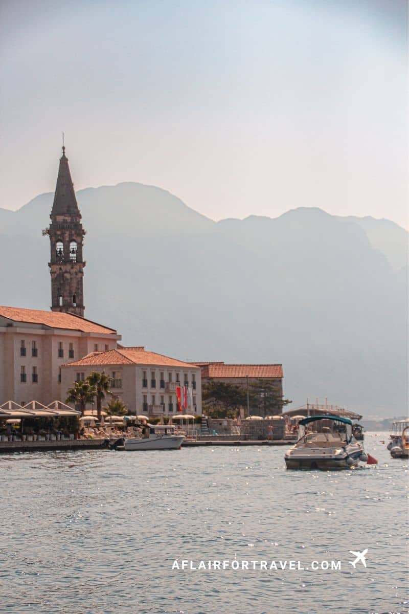 Boat view of Perast, Montenegro with mountains, waterfront buildings, and marina during a popular day trip from Dubrovnik.