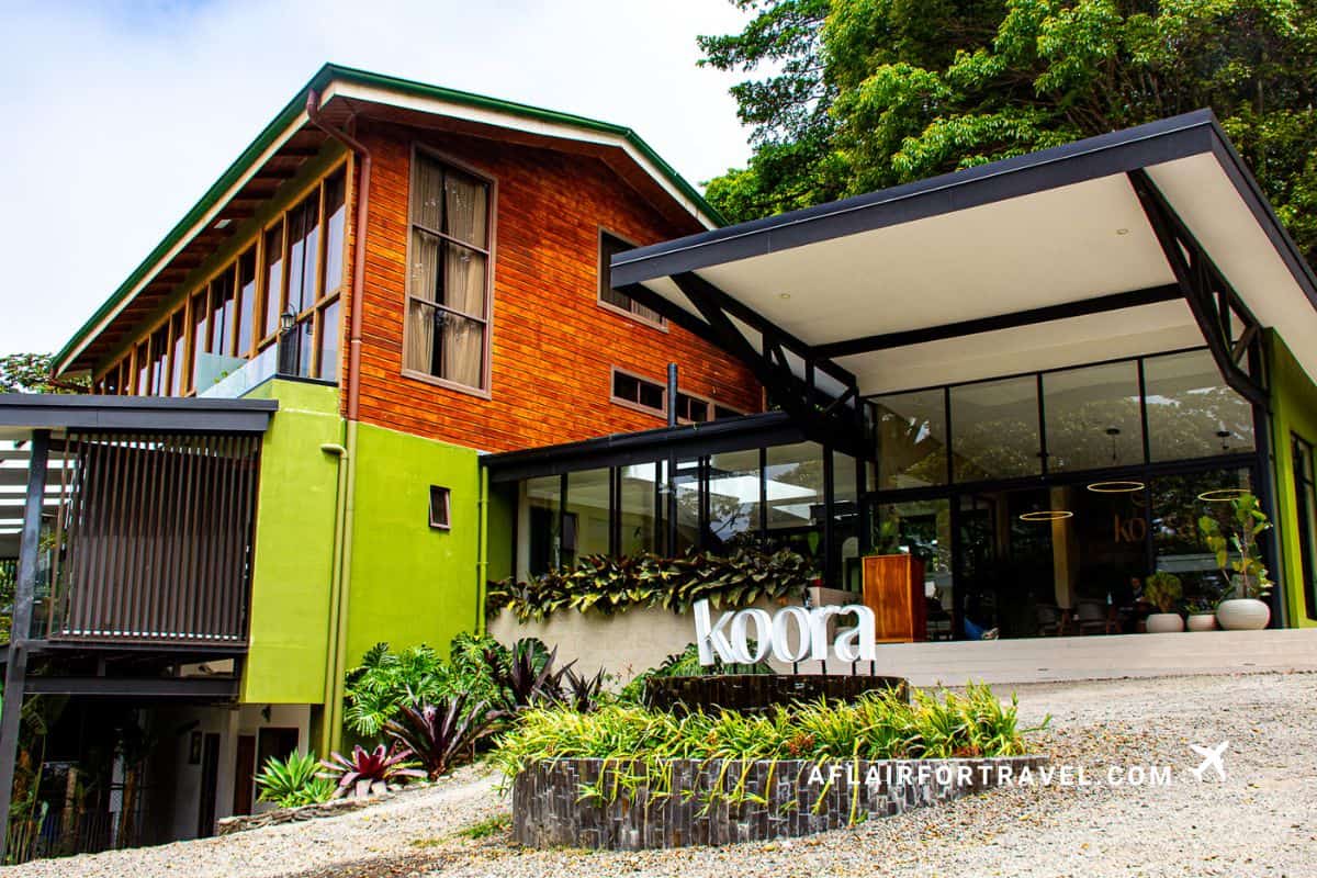 The exterior of Koora hotel in Monteverde, featuring a wooden upper story, lime green accents, and tropical landscaping