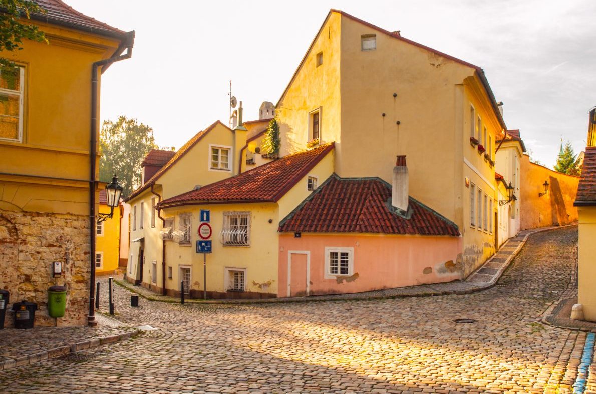 Golden-hour light on cobblestone streets and pastel houses in Nový Svět in the Hradčany district