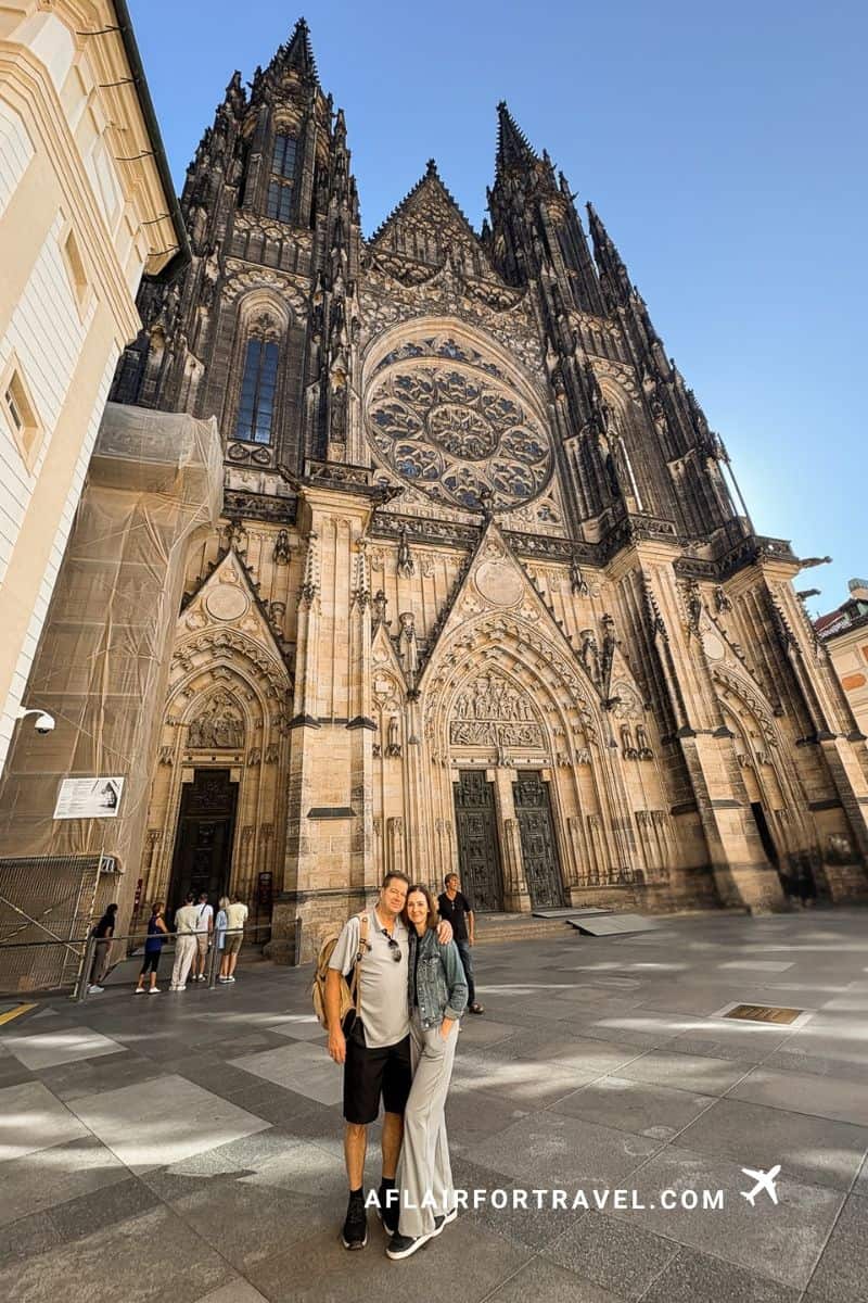 Couple standing in front of the twin spires and rose window of St. Vitus Cathedral in Prague Castle
