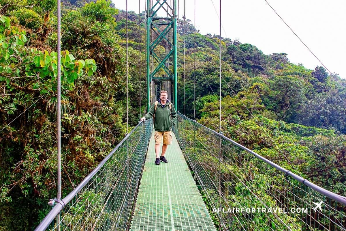 Visitor pausing mid-crossing on a tall suspension bridge over the cloud forest canopy in Monteverde, Costa Rica