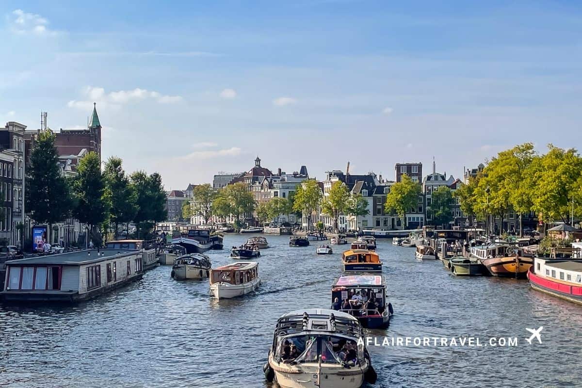 Boats crowding an Amsterdam canal with historic houseboats and canal houses lining the water