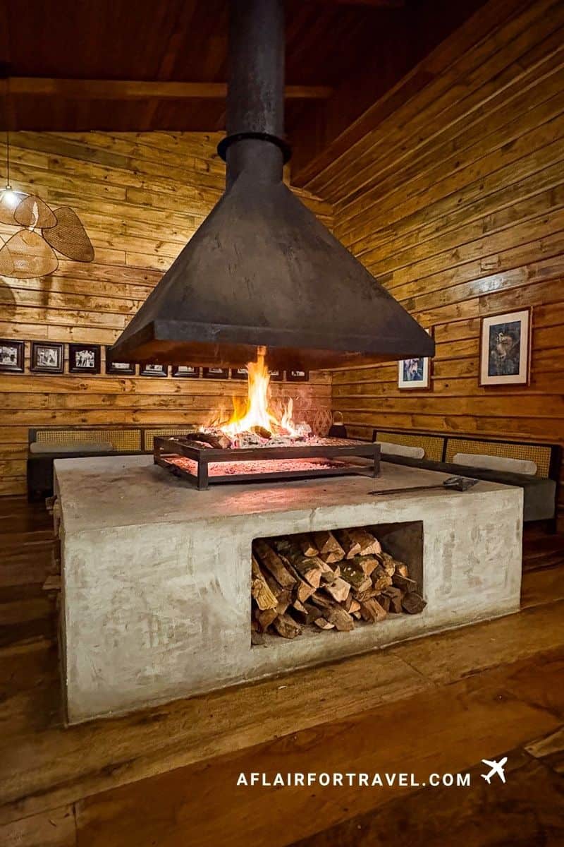 Central fire pit with chimney hood in a wood-paneled lounge at a Monteverde Costa Rica hotel