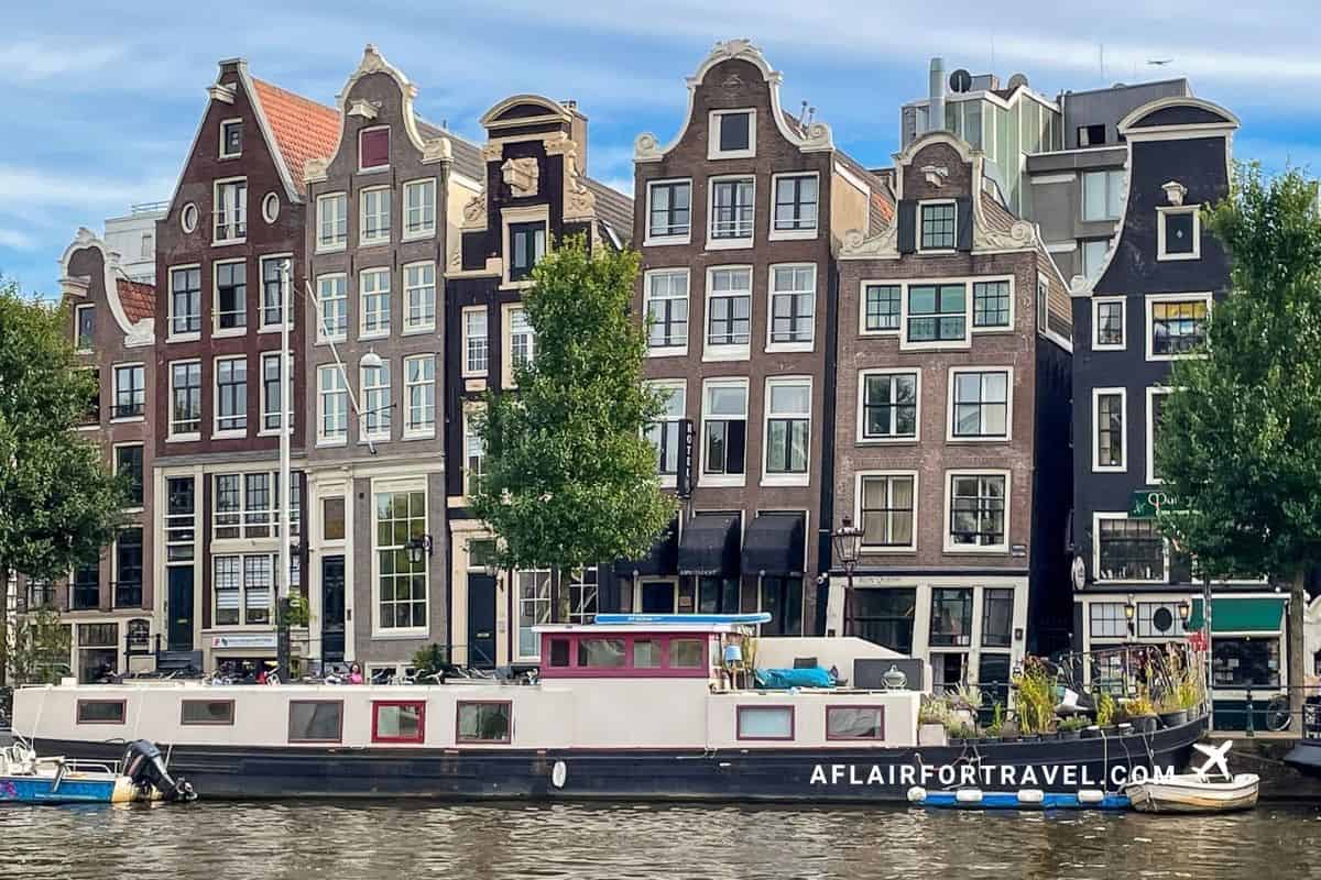 Traditional gabled canal houses and a houseboat along an Amsterdam waterway