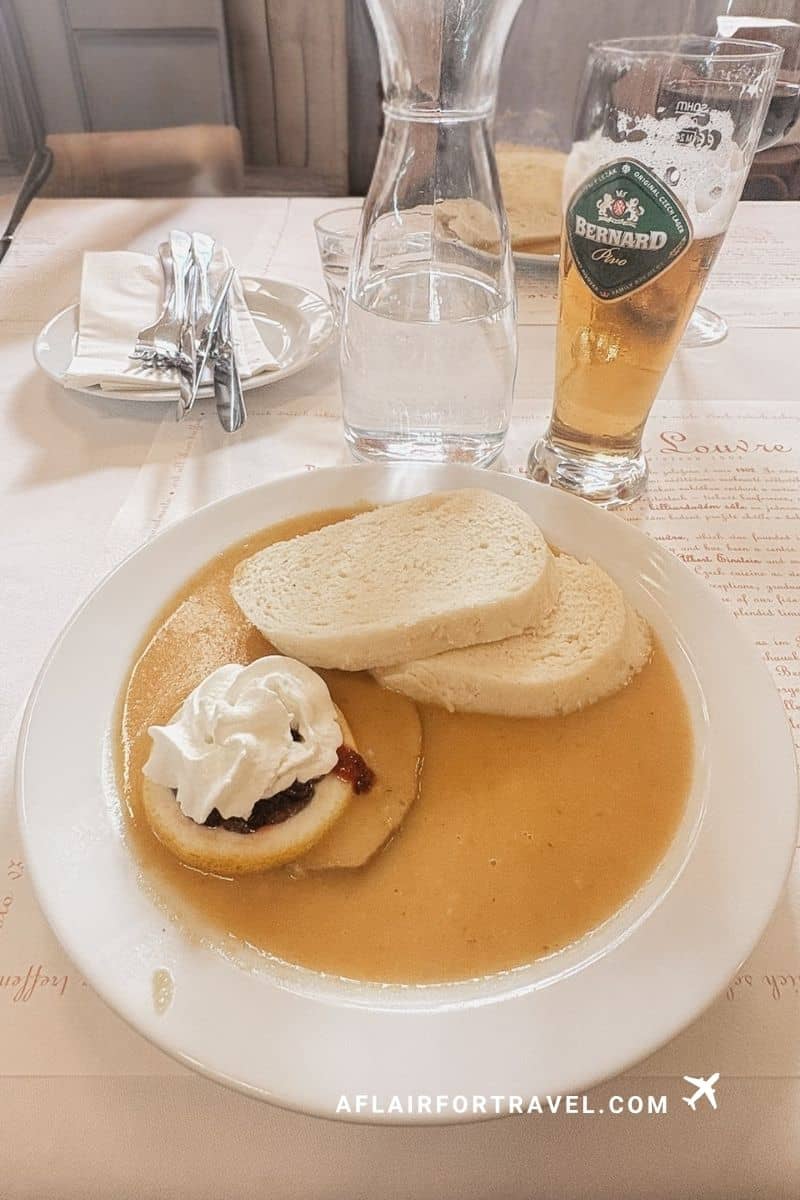 Czech Svíčková na smetaně with whipped cream and jam served with a Bernard beer