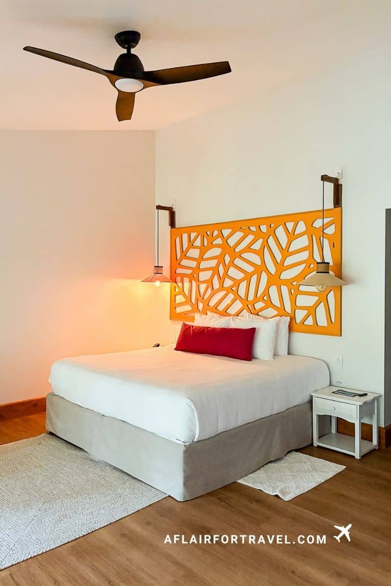 Bright hotel room with orange carved headboard and ceiling fan, Monteverde Costa Rica accommodations