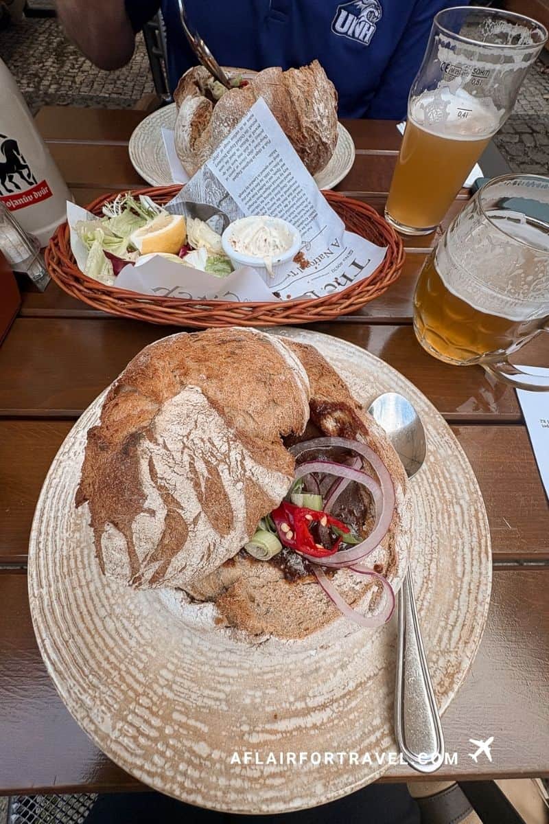 Traditional bread bowl goulash with pickled onions and peppers, paired with Czech beer