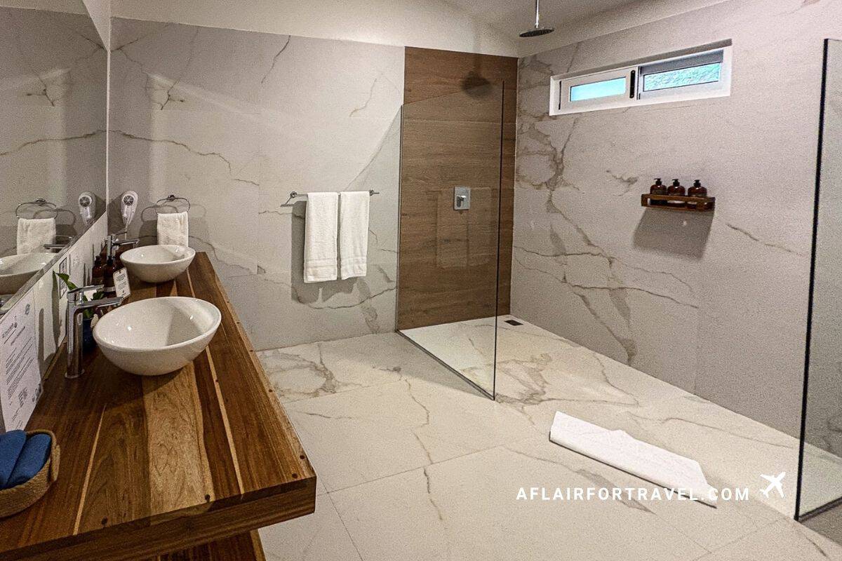 Spacious marble bathroom with double vanity and walk-in shower at a Monteverde Costa Rica hotel