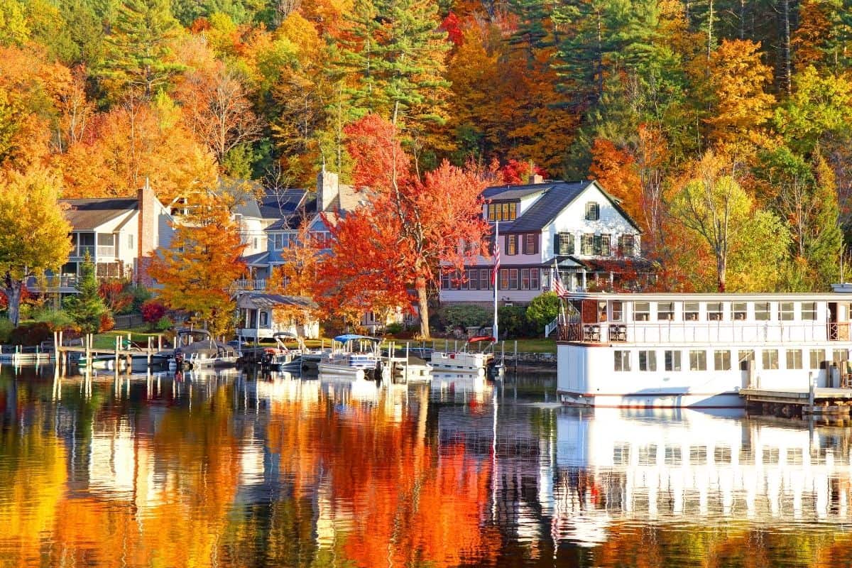 Lakeside houses and a docked sternwheeler boat in Lake Sunapee framed by peak fall foliage