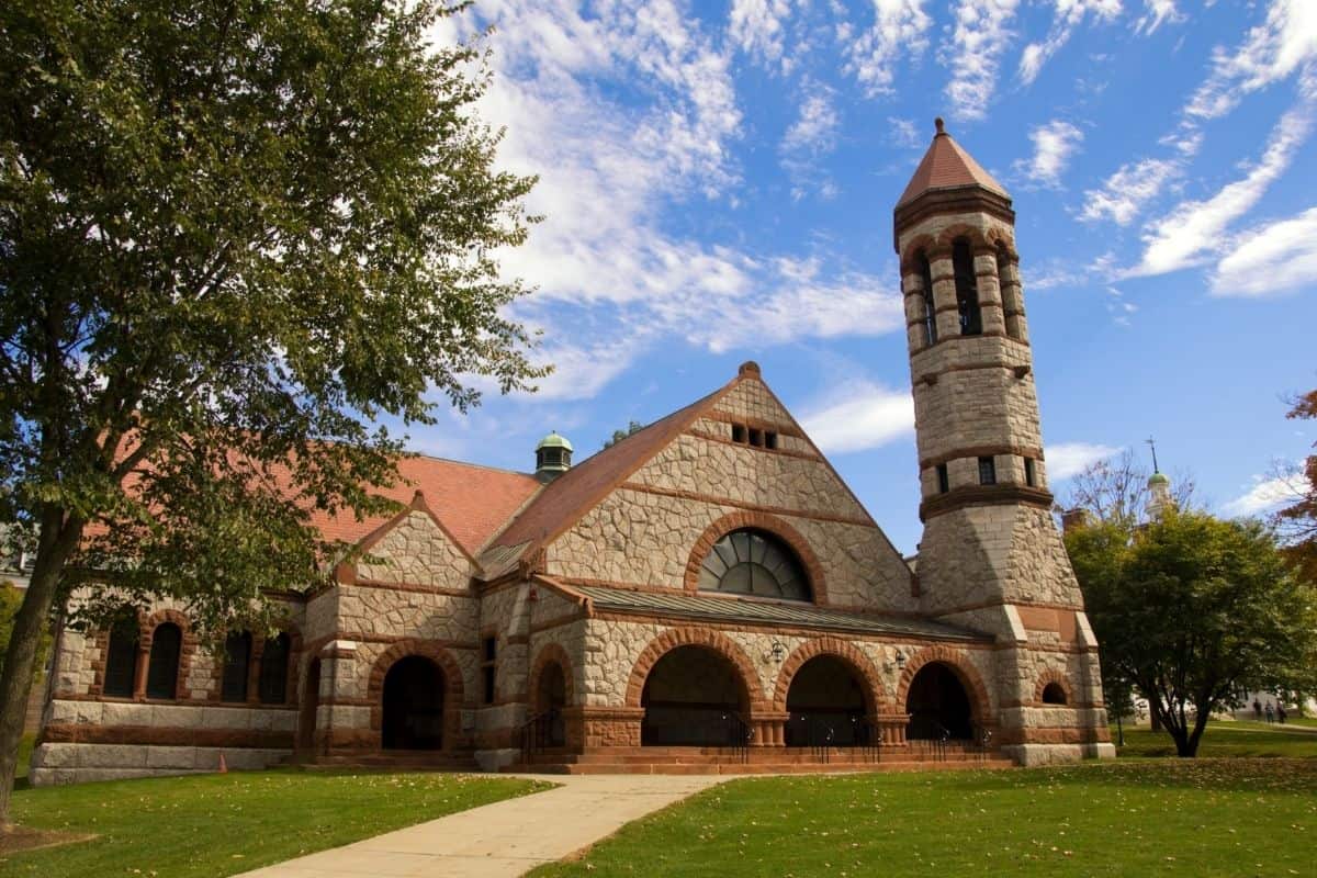 Campus church at Dartmouth University with a bell tower against a blue sky and green lawn