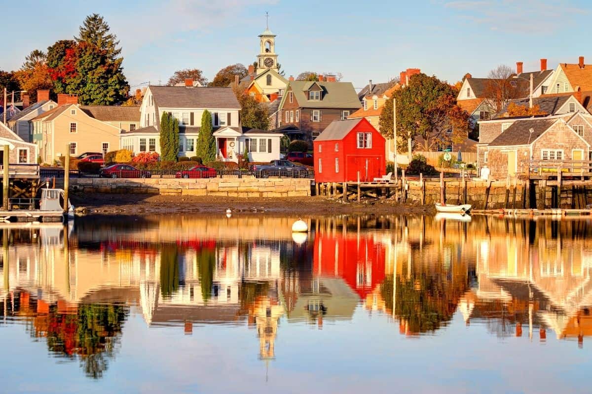 Reflections of a red boathouse and colonial homes in a Portsmouth New Hampshire harbor