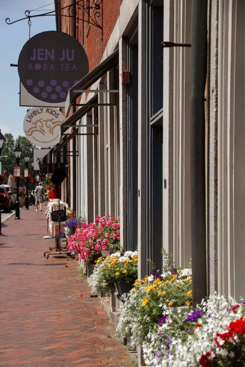 Flower-lined storefronts and shops on a Newburyport shopping street