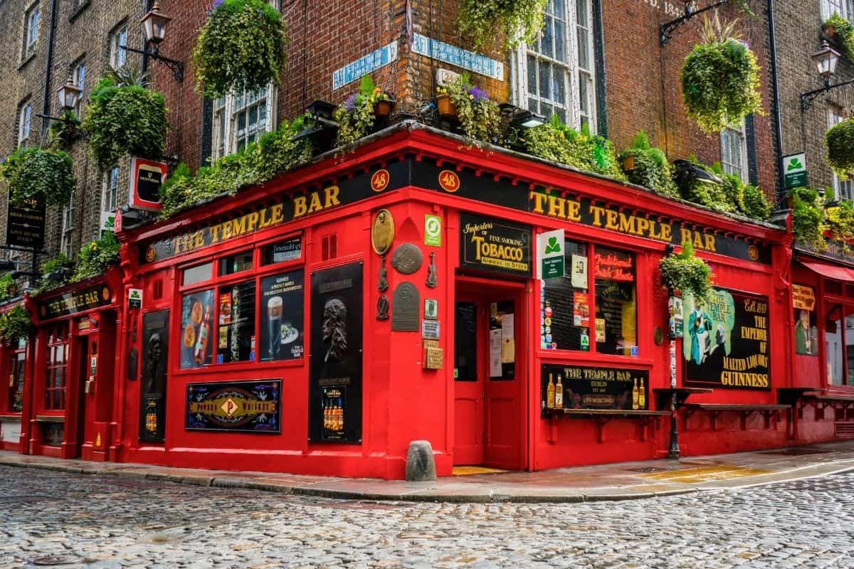 The Temple Bar's red facade on a cobblestone street in Dublin, a first-time trip to Europe classic