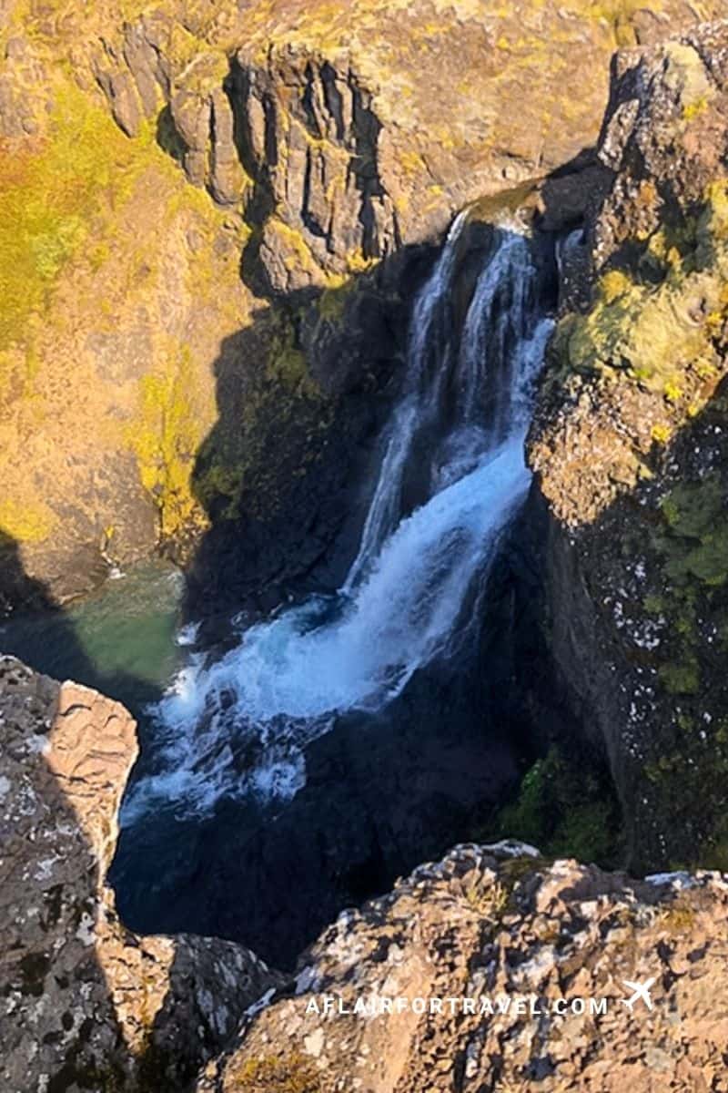 Aerial view of a waterfall cutting through Iceland's rocky canyon