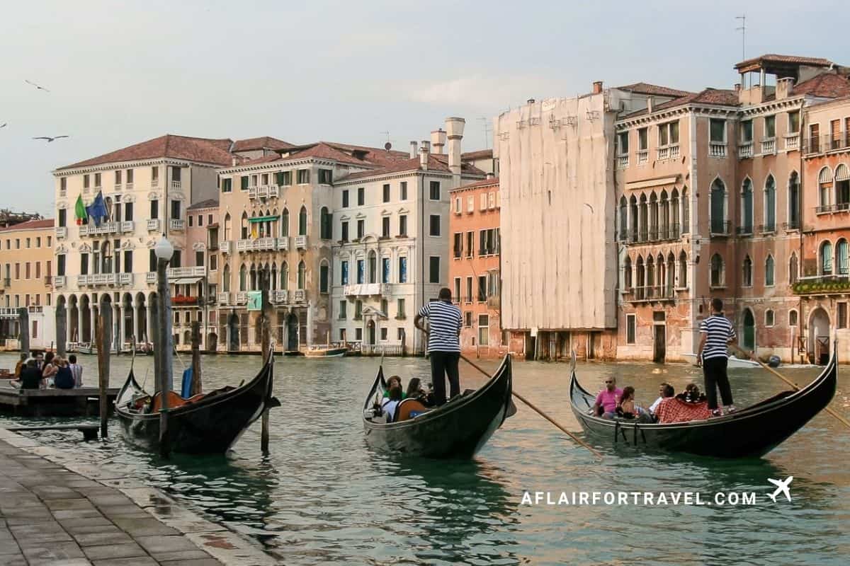 Gondolas and gondoliers navigating a canal lined with historic buildings in Venice, Italy