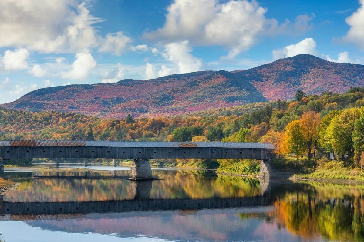 Cornish-Windsor Covered Bridge stretching across the Connecticut River with fall foliage on the hills, New Hampshire in the fall